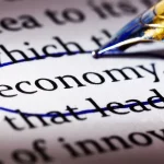 Palavra economy destacada em texto com caneta azul, representando alfabetização financeira e educação econômica em 2026.