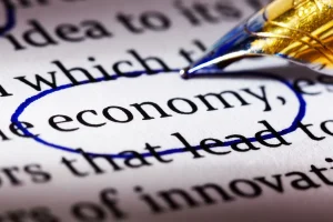 Palavra economy destacada em texto com caneta azul, representando alfabetização financeira e educação econômica em 2026.