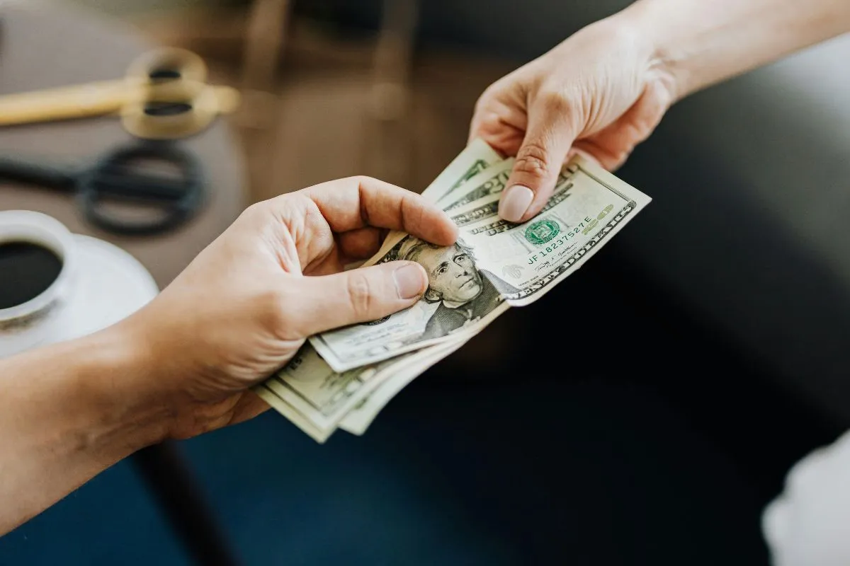 Mãos trocando notas de dólar americano em pagamento ou transação financeira