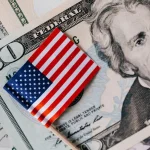 Bandeira dos Estados Unidos sobre notas de dólar americano destacando economia e moeda