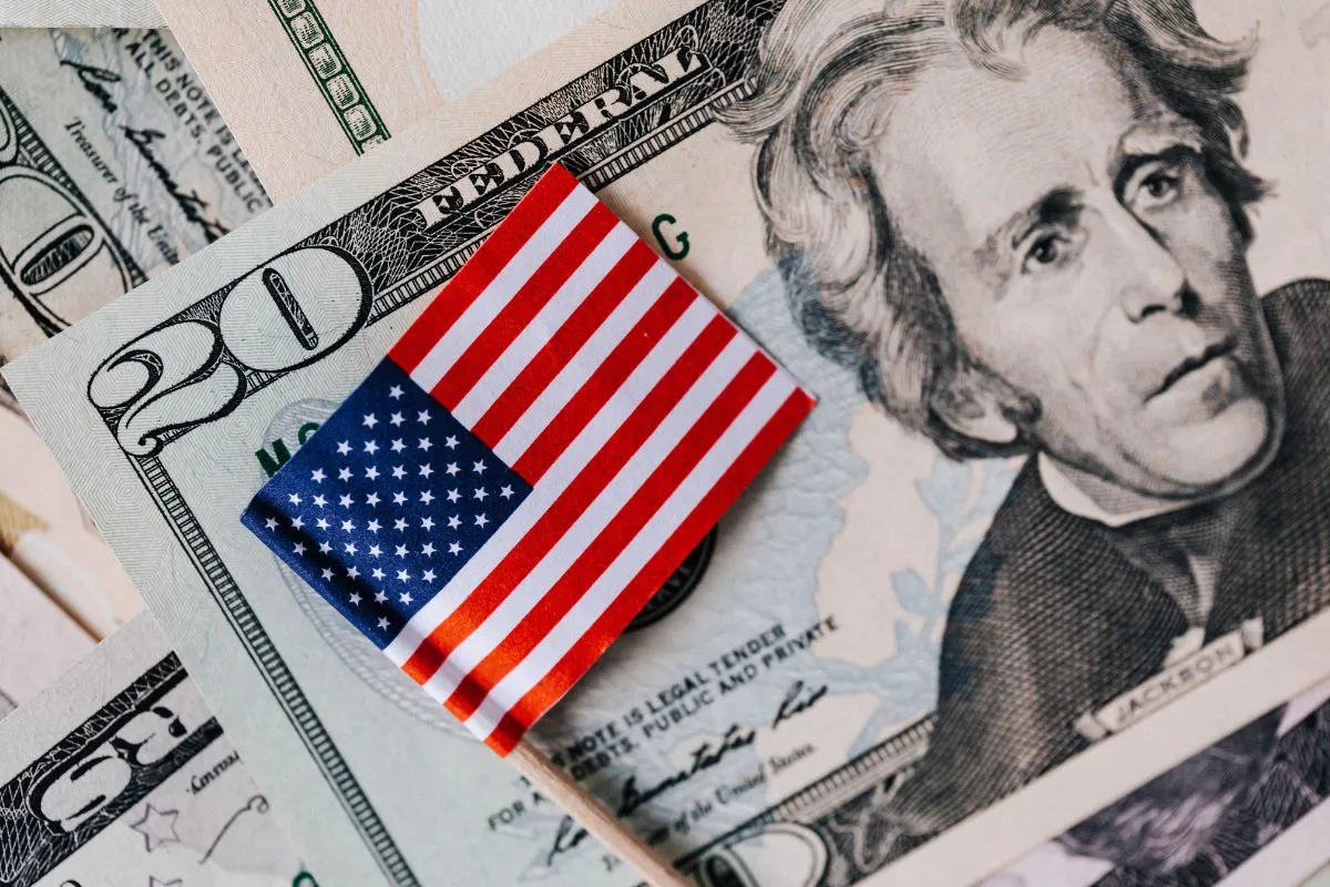 Bandeira dos Estados Unidos sobre notas de dólar americano destacando economia e moeda