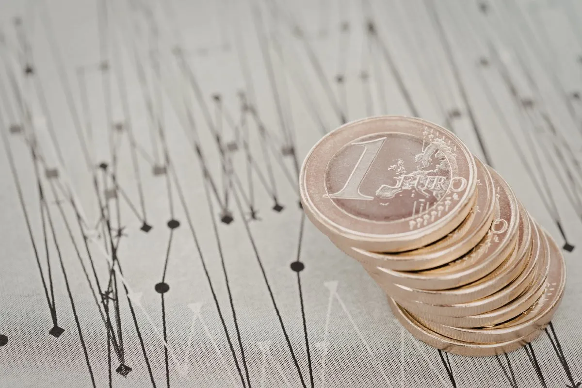 Pilha de moedas de euro posicionadas sobre gráfico de linhas representando mercado financeiro