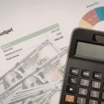 Calculadora, notas de dólar e gráfico de orçamento representando controle de gastos e contas públicas do governo