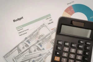 Calculadora, notas de dólar e gráfico de orçamento representando controle de gastos e contas públicas do governo