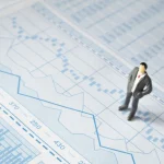 Miniatura de empresário sobre gráfico financeiro representando análise do PIB e economia