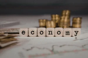 Cubos formando a palavra economy sobre gráficos financeiros, representando reforma econômica e modernização do mercado