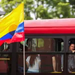 Uma bandeira colombiana tremula, enquanto pessoas andam de ônibus durante o segundo turno das eleições - 21/6/2026 | Foto: Juan David Duque/Reuters