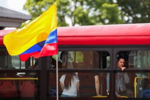 Uma bandeira colombiana tremula, enquanto pessoas andam de ônibus durante o segundo turno das eleições - 21/6/2026 | Foto: Juan David Duque/Reuters