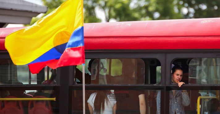 Uma bandeira colombiana tremula, enquanto pessoas andam de ônibus durante o segundo turno das eleições - 21/6/2026 | Foto: Juan David Duque/Reuters
