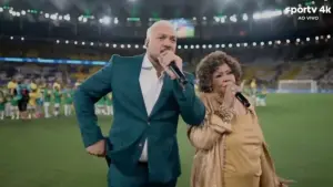Na imagem, Belo e Alcione cantam o Hino Nacional antes do amistoso da seleção / Foto: Reprodução/SporTV