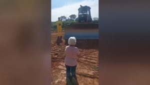 Maria da Paz, de 78 anos, se ajoelha diante de máquinas que tentam desapropriar seu terreno | Foto: Reprodução/Redes sociais