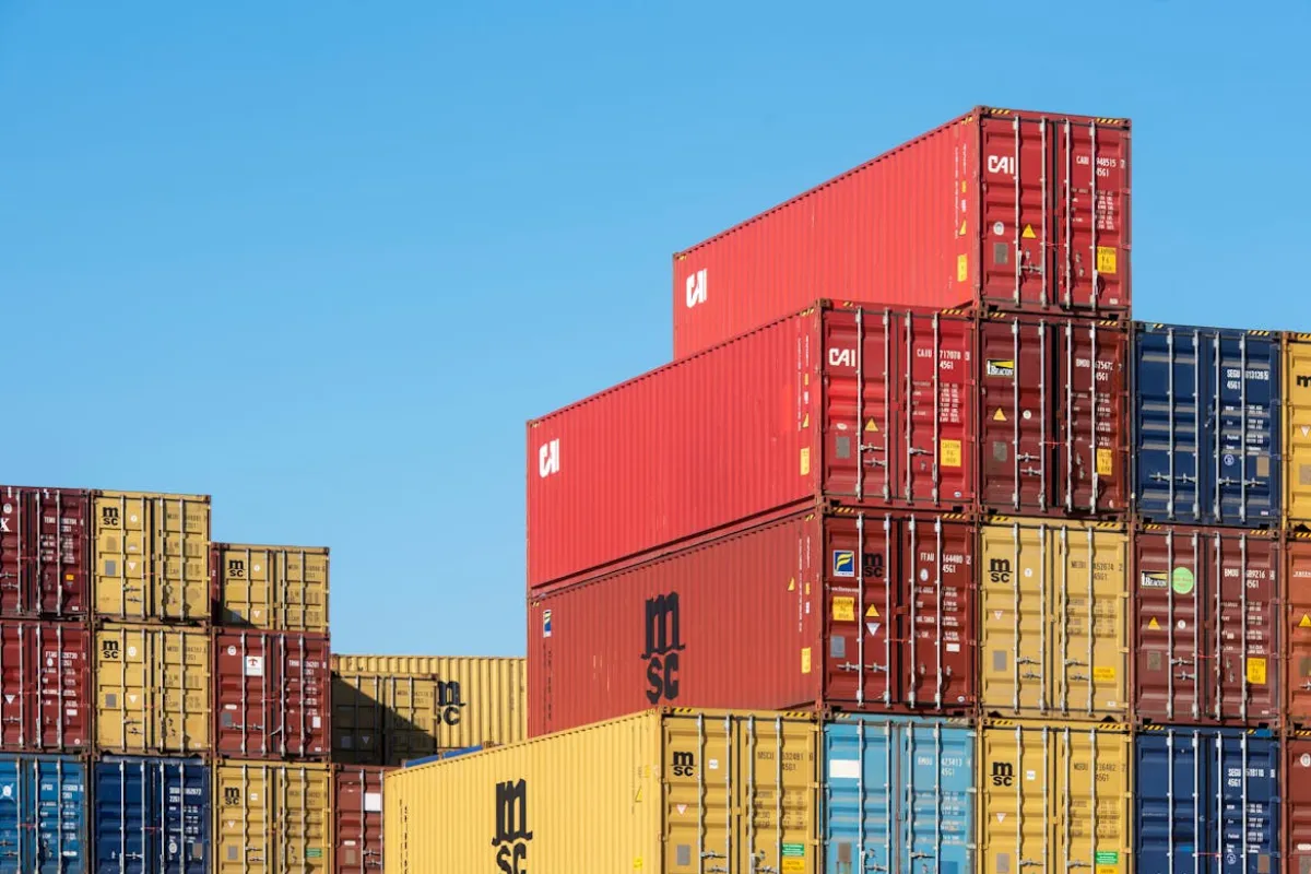 Contêineres coloridos empilhados em área de armazenamento de terminal portuário.