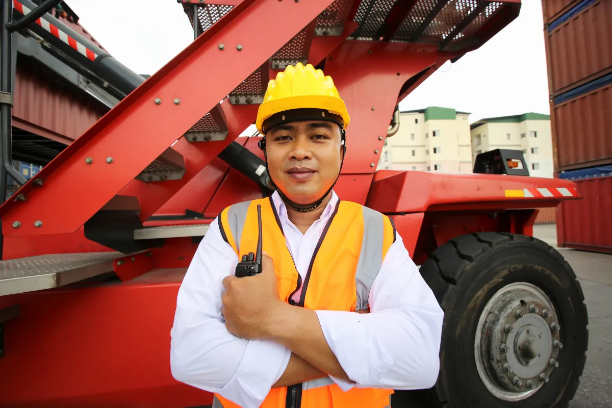 Supervisor de logística usando capacete e rádio comunicador em terminal de contêineres.