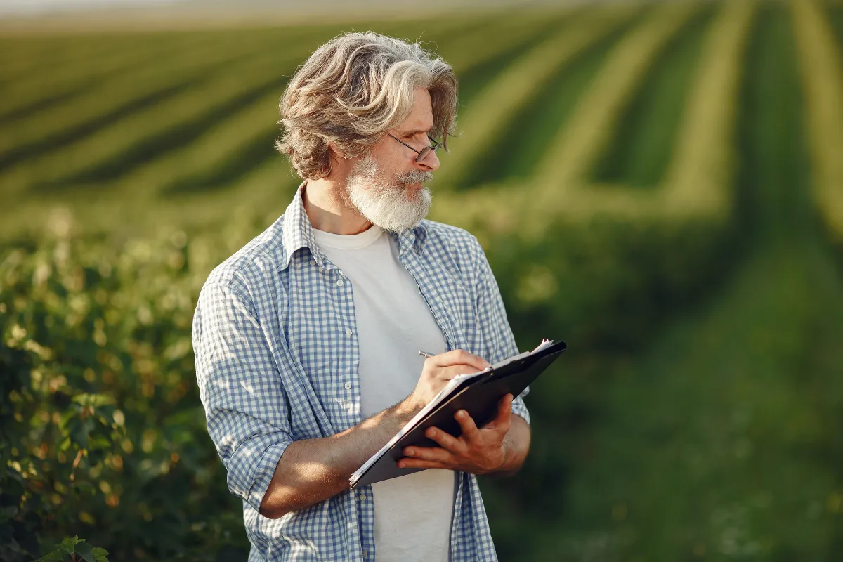 Produtor rural registra informações da lavoura em prancheta durante avaliação de culturas destinadas ao mercado agrícola.