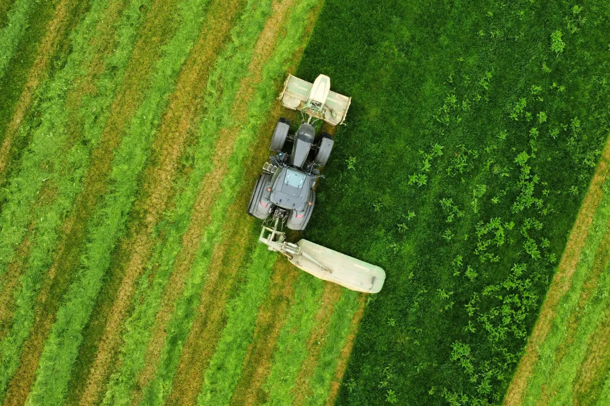 Vista aérea de trator trabalhando em área verde durante atividade agrícola ligada à cadeia do agronegócio.