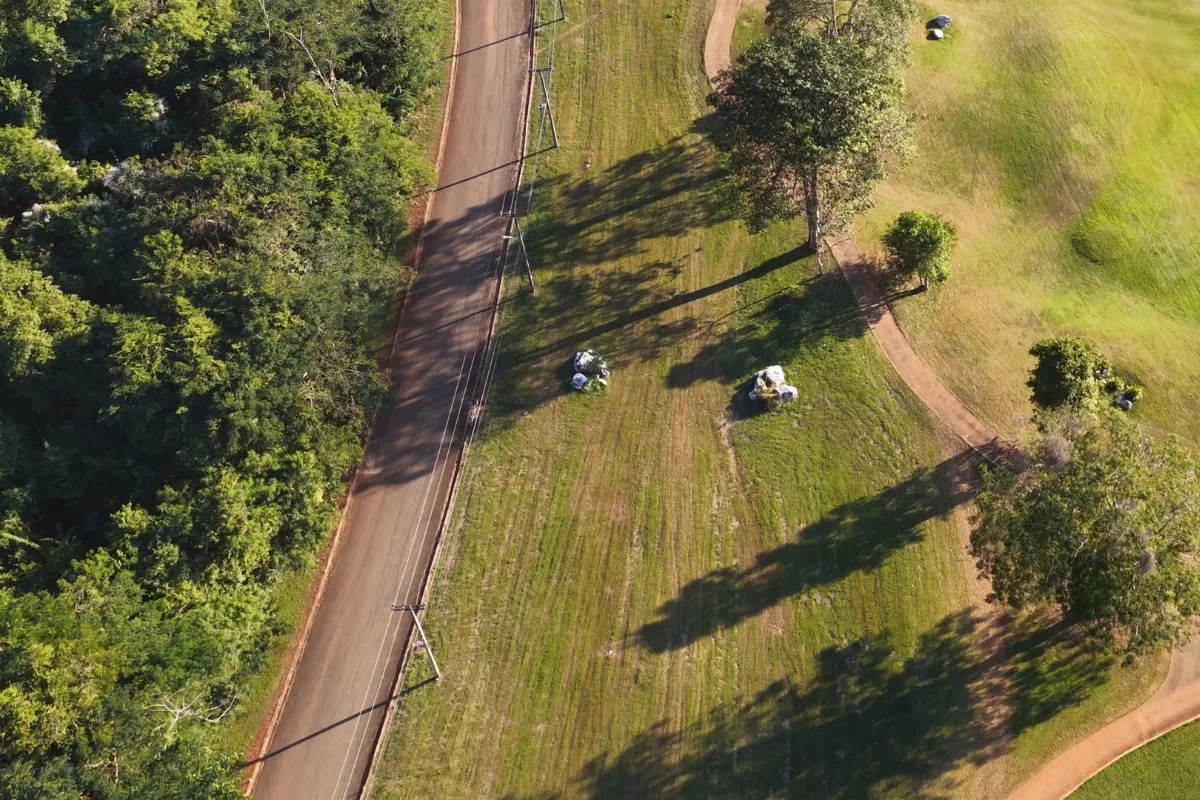 Vista aérea de área verde preservada ao lado de estrada rural, destacando a integração entre produção e conservação ambiental.
