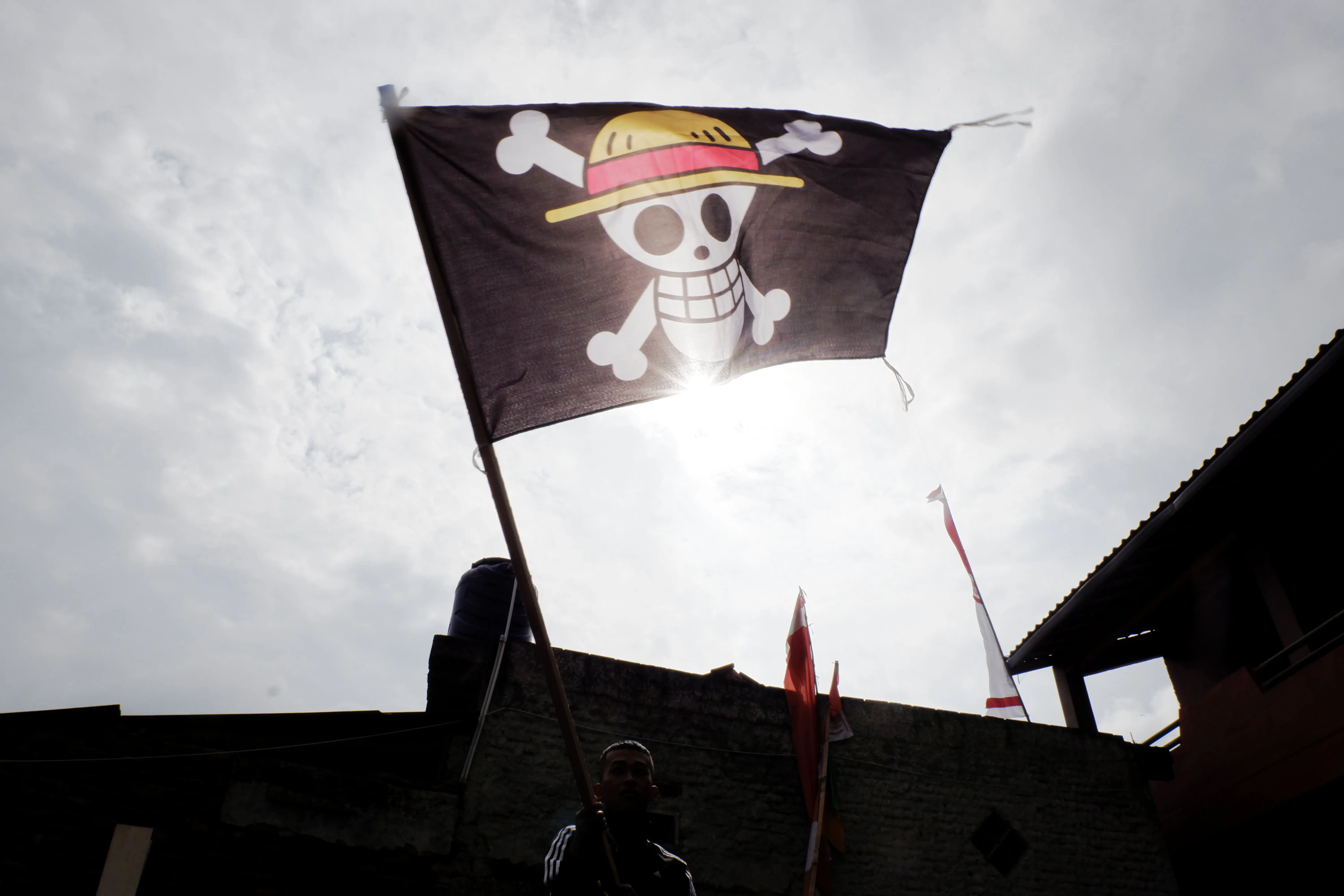 Homens seguram a bandeira pirata do anime japonês ‘One Piece’ em Garut, Java Ocidental, Indonésia - 12/8/2025 | Foto: Algi Febri Sugita/Zuma Press Wire/Reuters